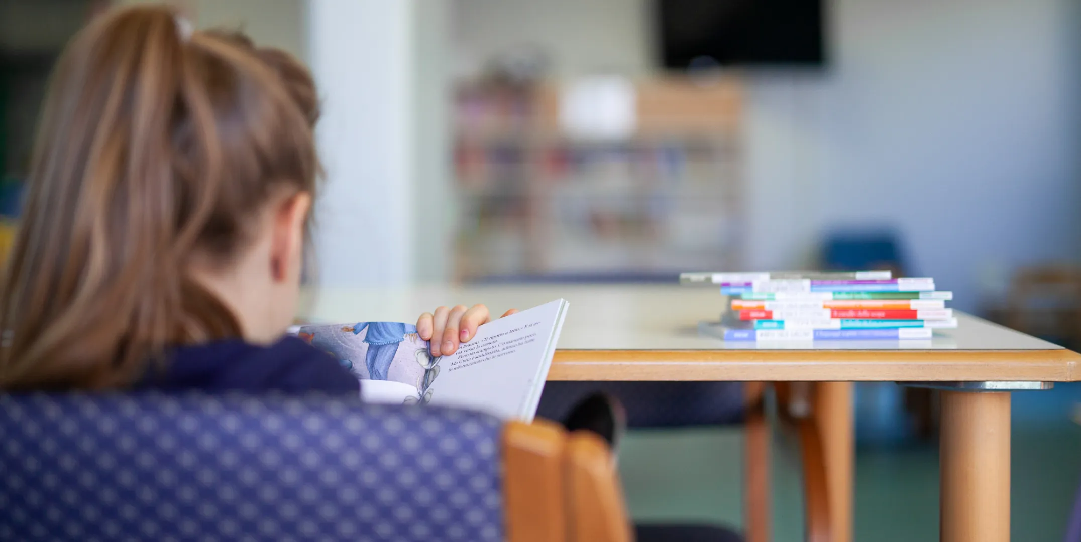 Bambina che legge un libro a scuola
